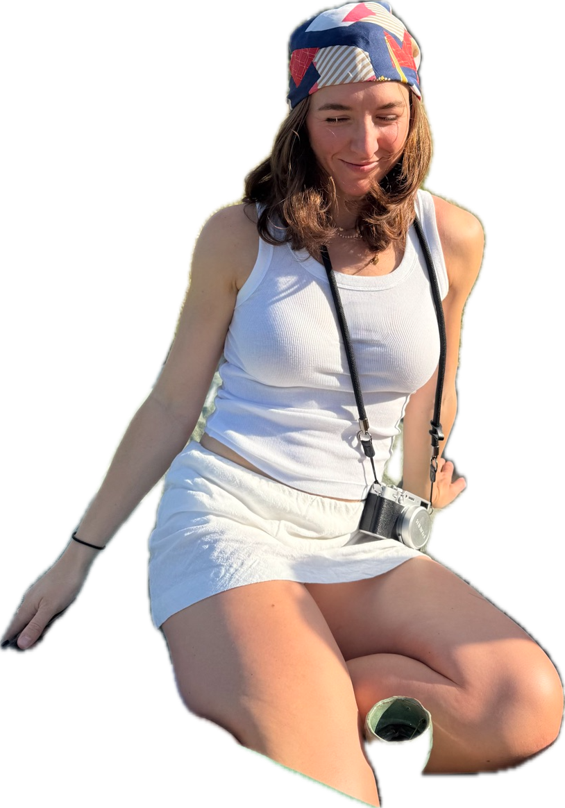 Sophie Dolan sitting in a sunny field with a camera around her neck